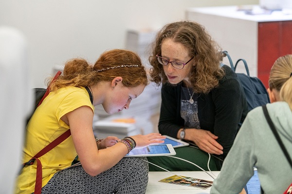 Lehrerin erklärt Schülerin einen Hinweis im Tablet