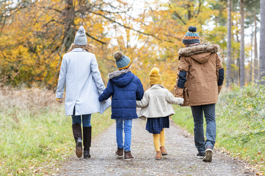 Children holding hands of parents while walking on forest path (KEYSTONE/WESTEND61/WILLIAM PERUGINI)